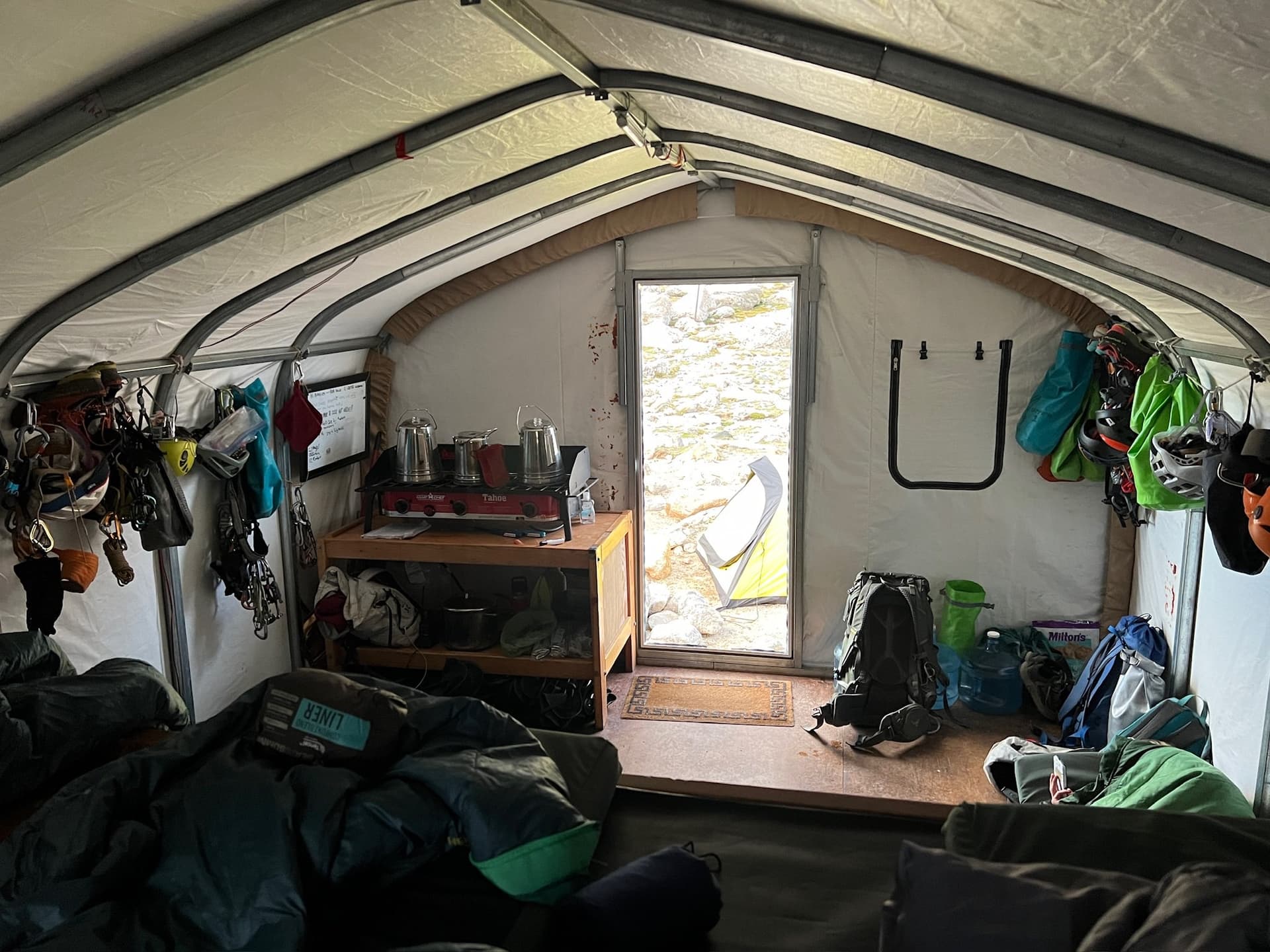 A room with a bunk bed and a door with lots of gear.