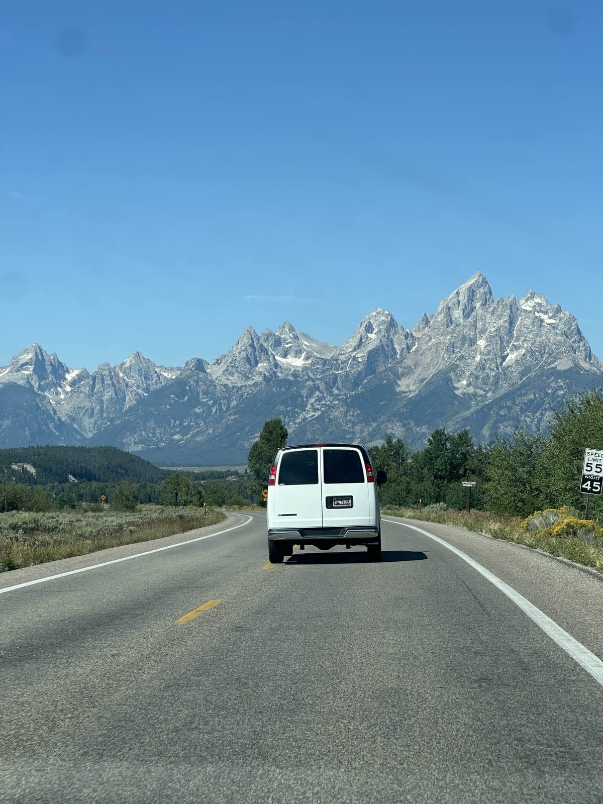 A van driving toward the Teton range on a highway